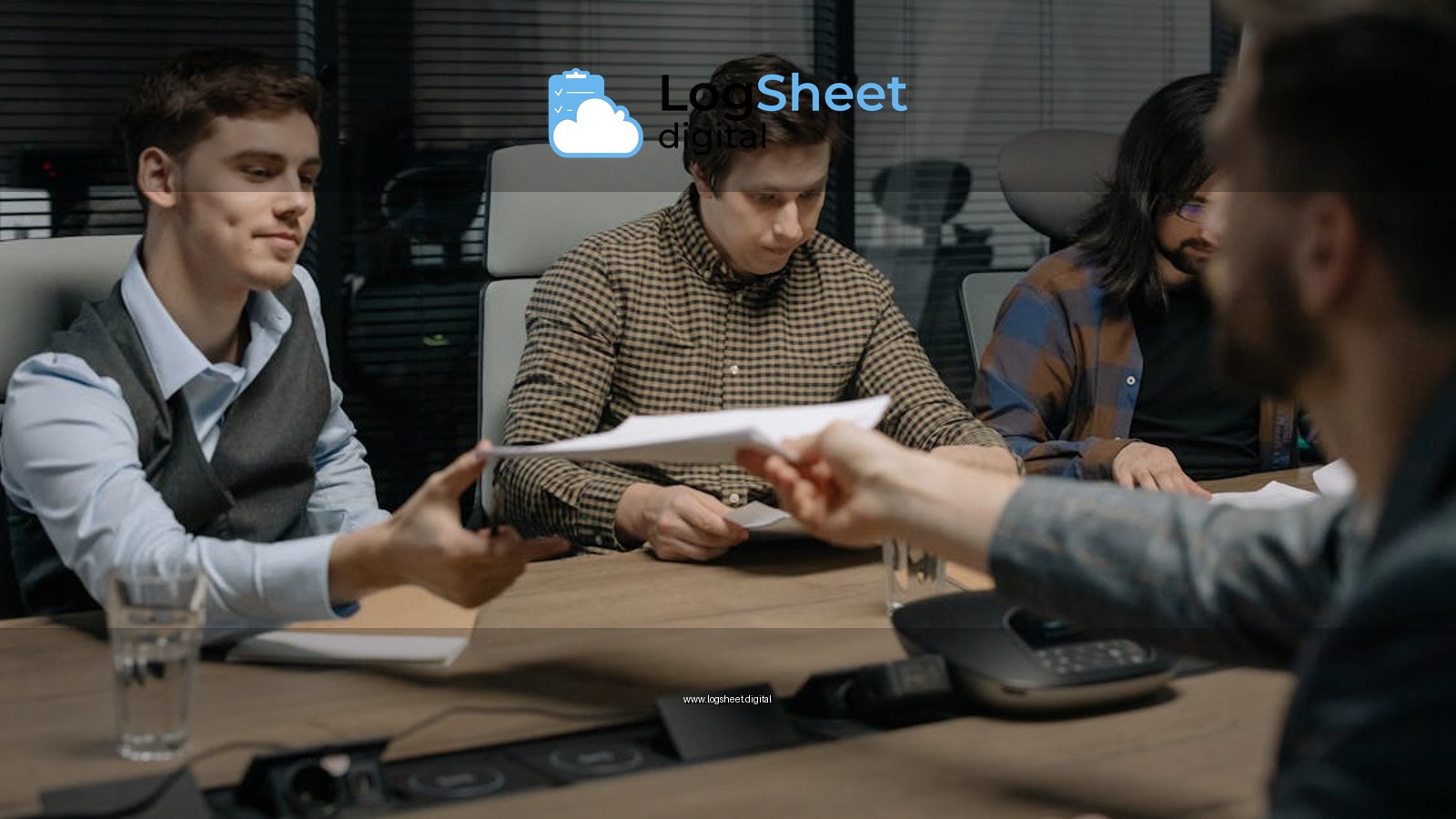 Four professionals exchanging documents during a meeting in an office setting.