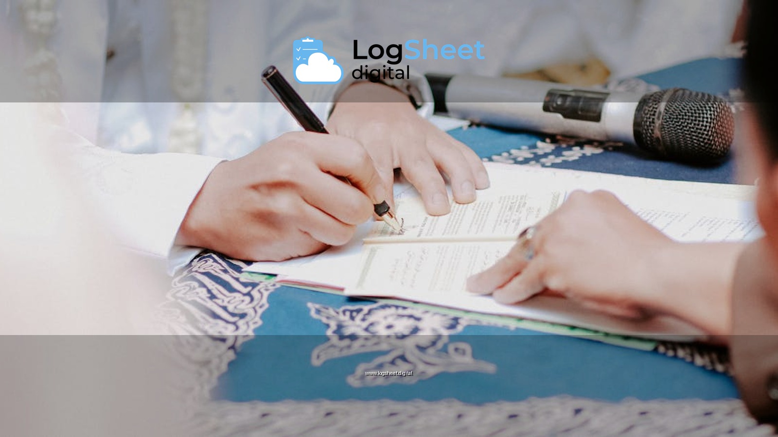 Close-up of hands signing wedding documents with microphone on table.