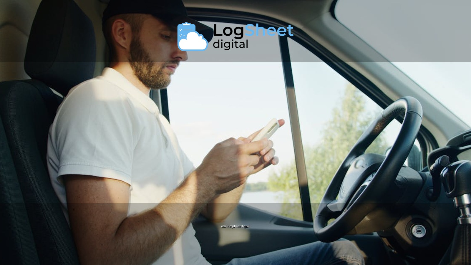 Side view of a man using a smartphone in a parked vehicle on a sunny day.