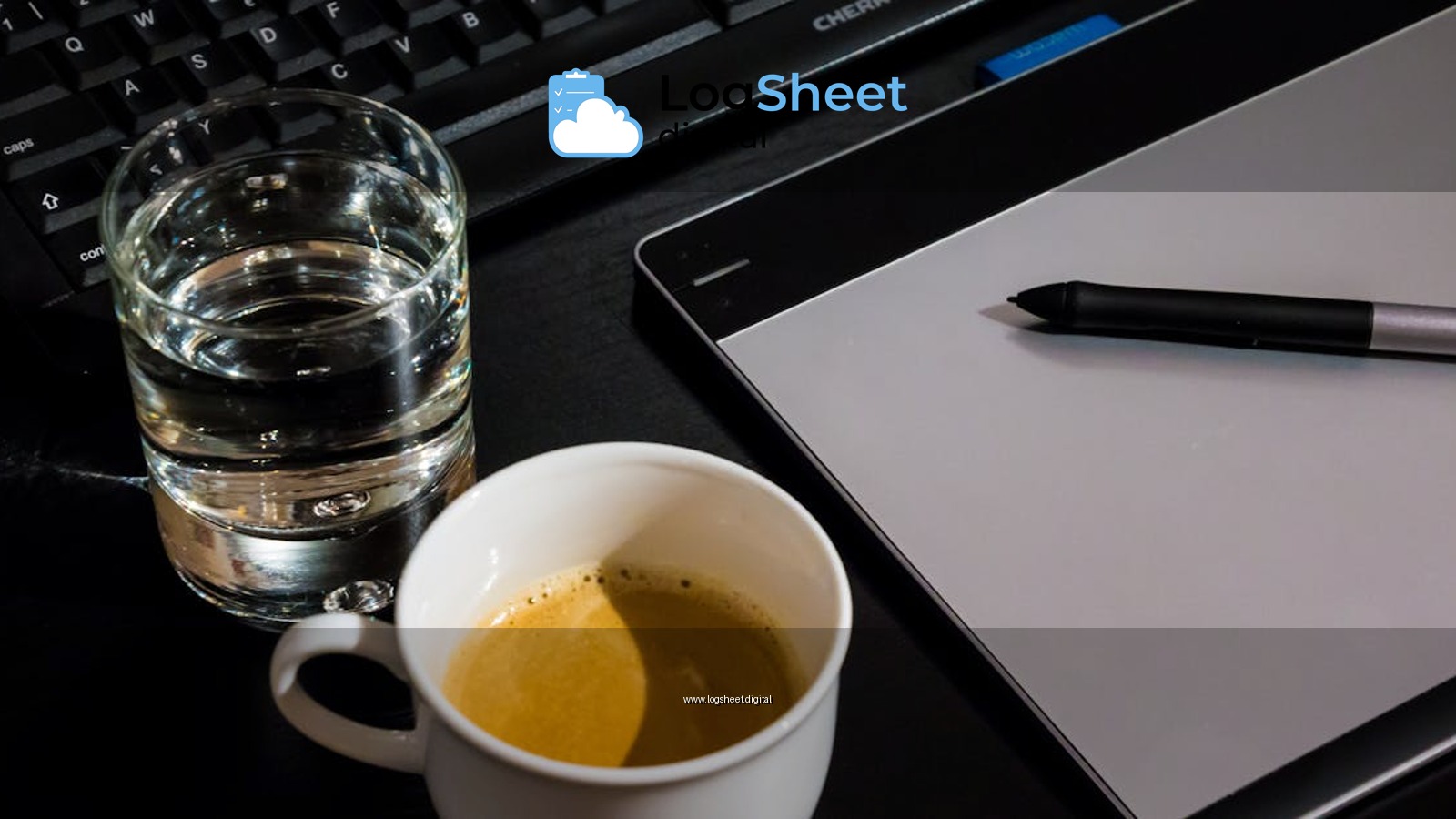 Office desk setup with a coffee cup, glass of water, tablet, pen, and keyboard.