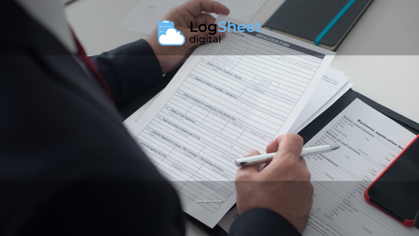 A businessman in a black suit reviews a printed application form with a pen on his desk.