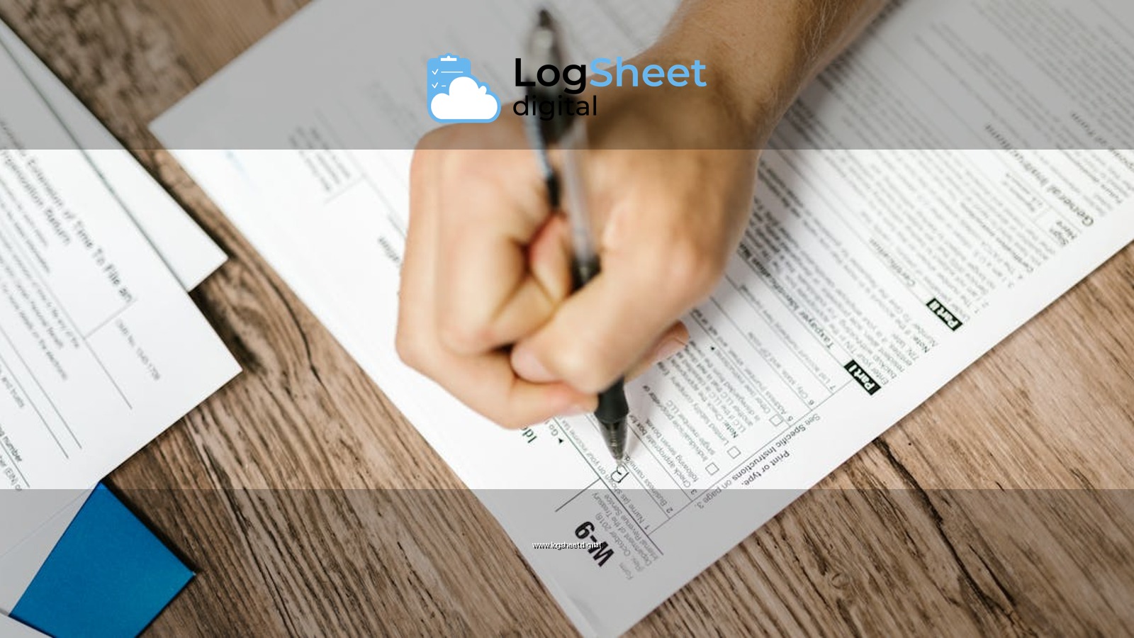 Hand writing on a W-9 tax form using a ballpoint pen on wooden desk.