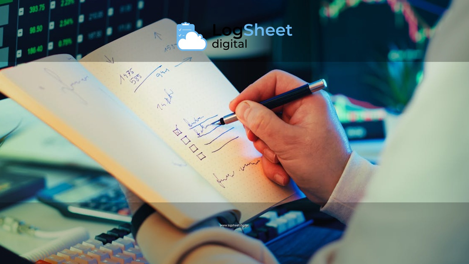 A businessman writes notes in a notebook while analyzing stock market data on a computer screen.