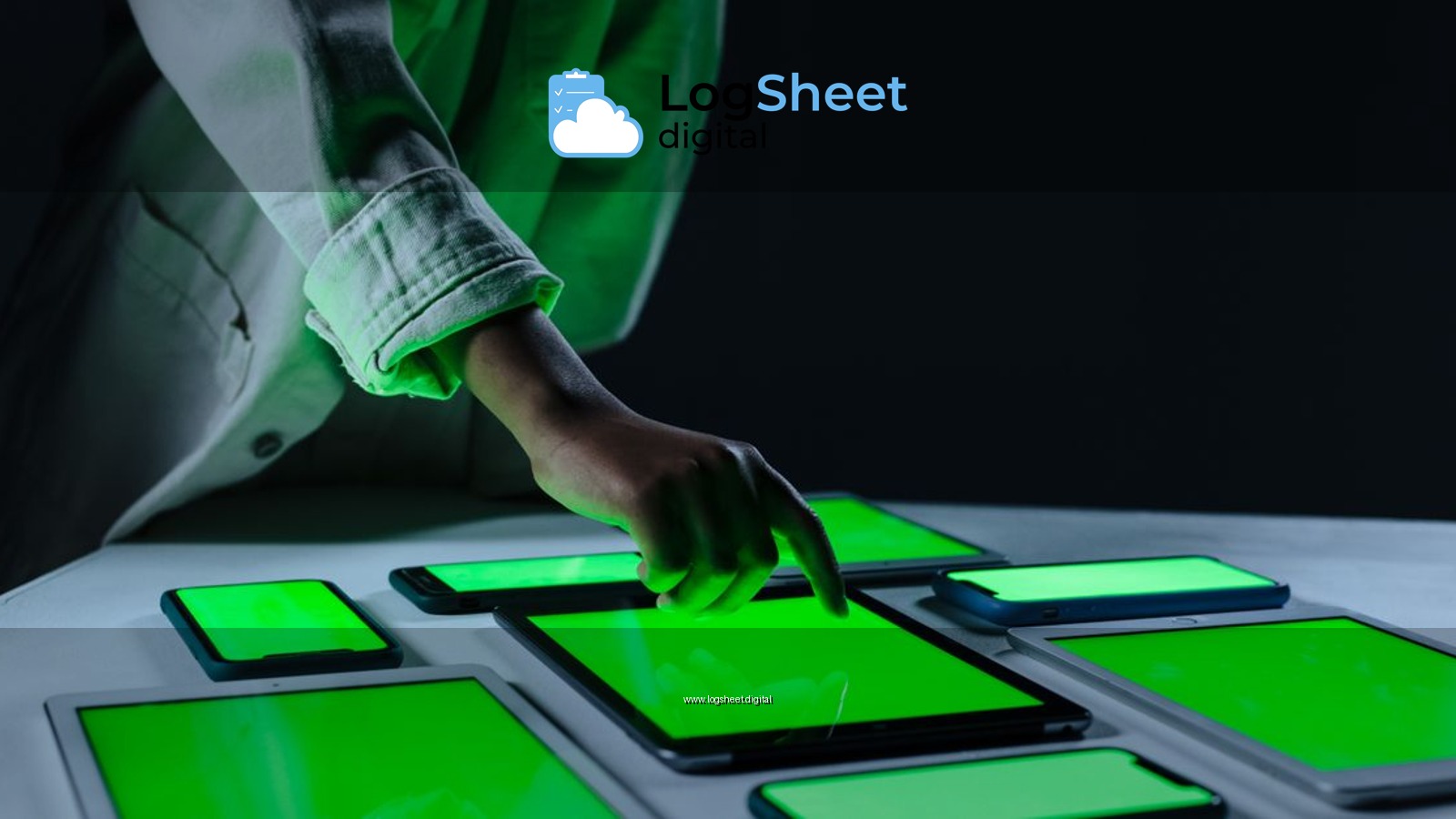 Hand interacting with multiple digital tablets on a green screen setup indoors.