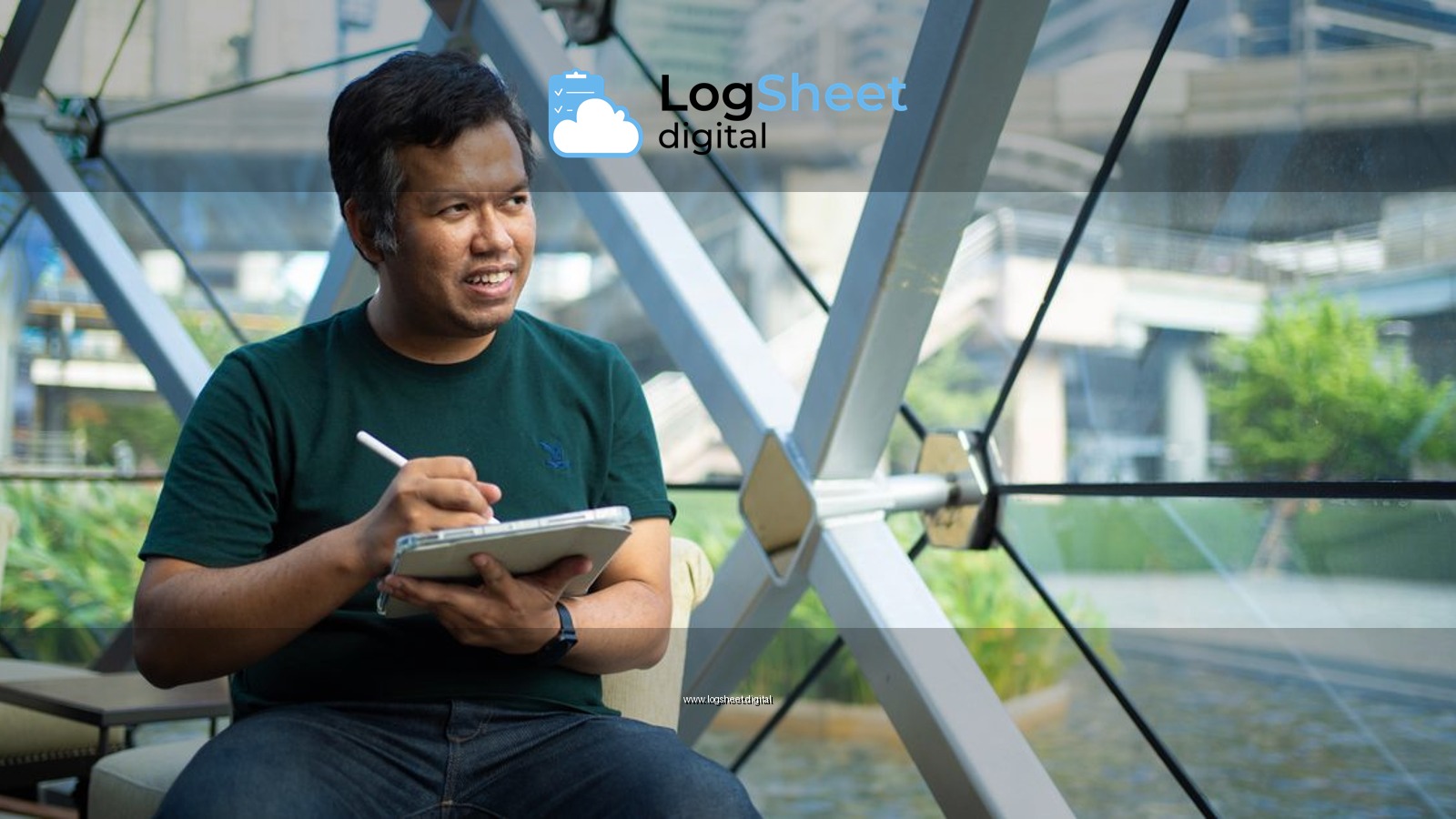 An Asian man sketches ideas on a digital tablet in a modern Bangkok café, highlighting remote work lifestyle.