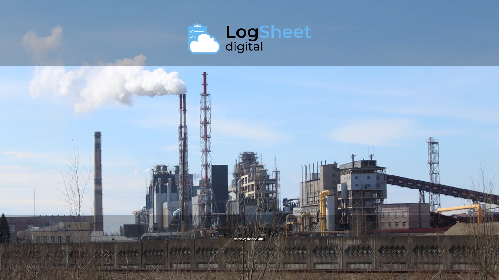 An industrial factory with smoke emissions against a clear blue sky.