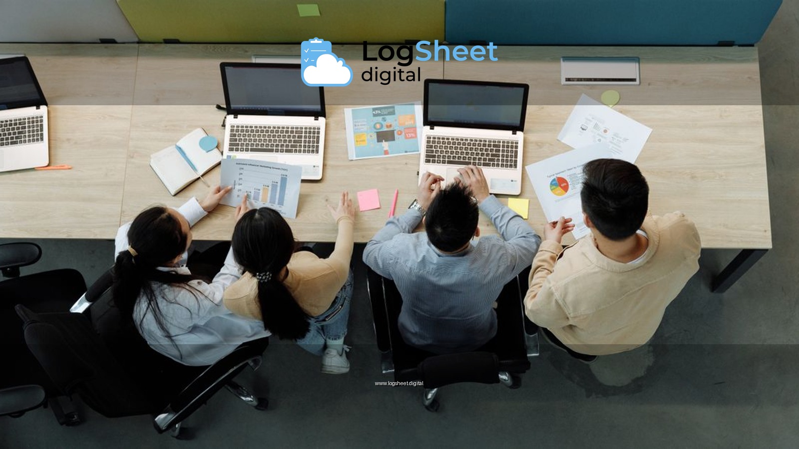 Aerial view of four colleagues working with laptops and documents at a shared desk.