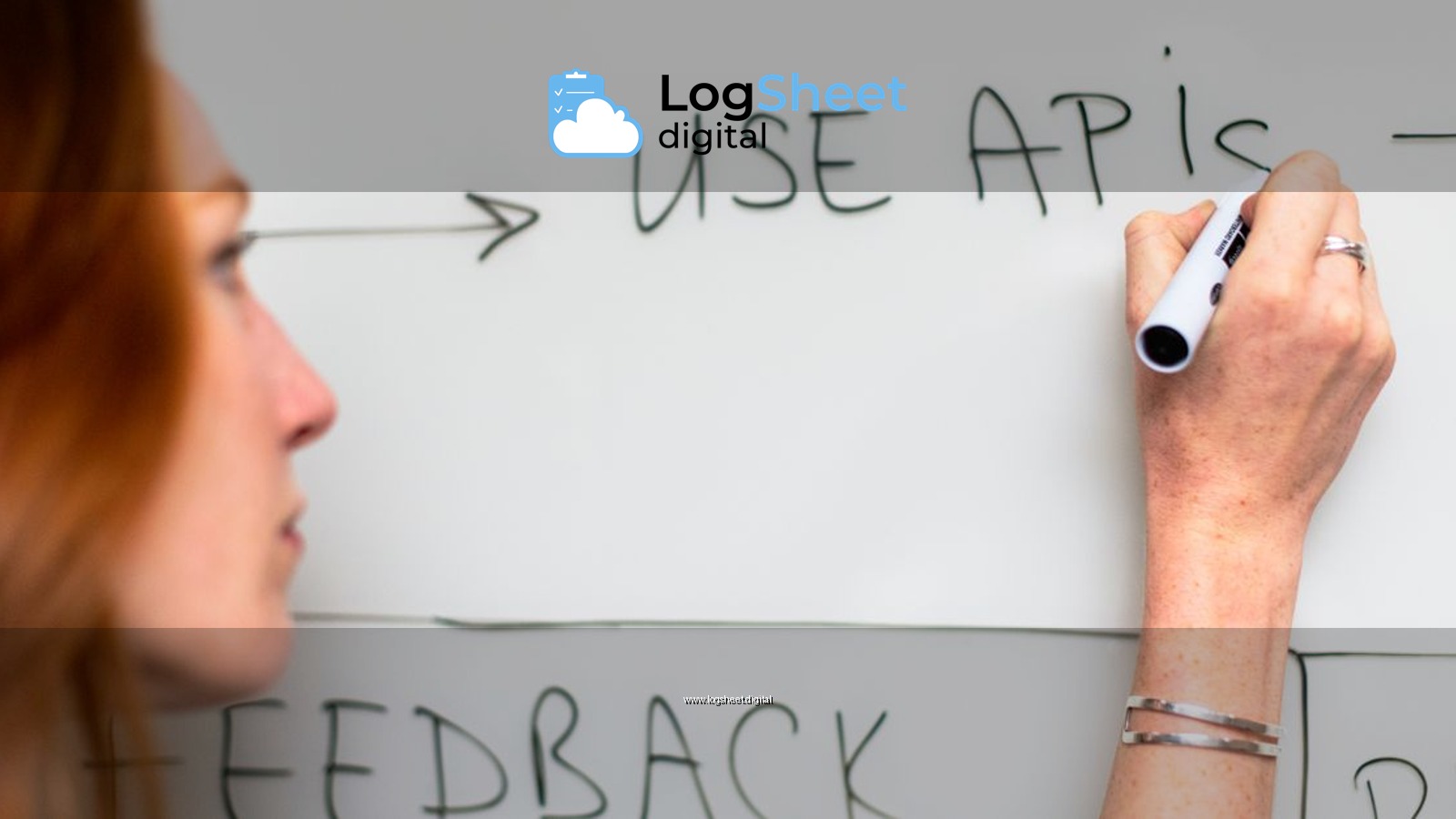 A woman writes 'Use APIs' on a whiteboard, focusing on software planning and strategy.