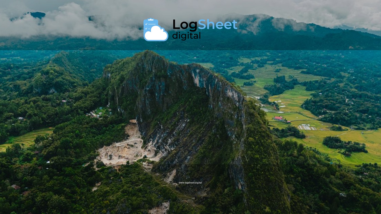 Aerial view of a lush, mountainous landscape in Indonesia with clouds hugging the peaks.