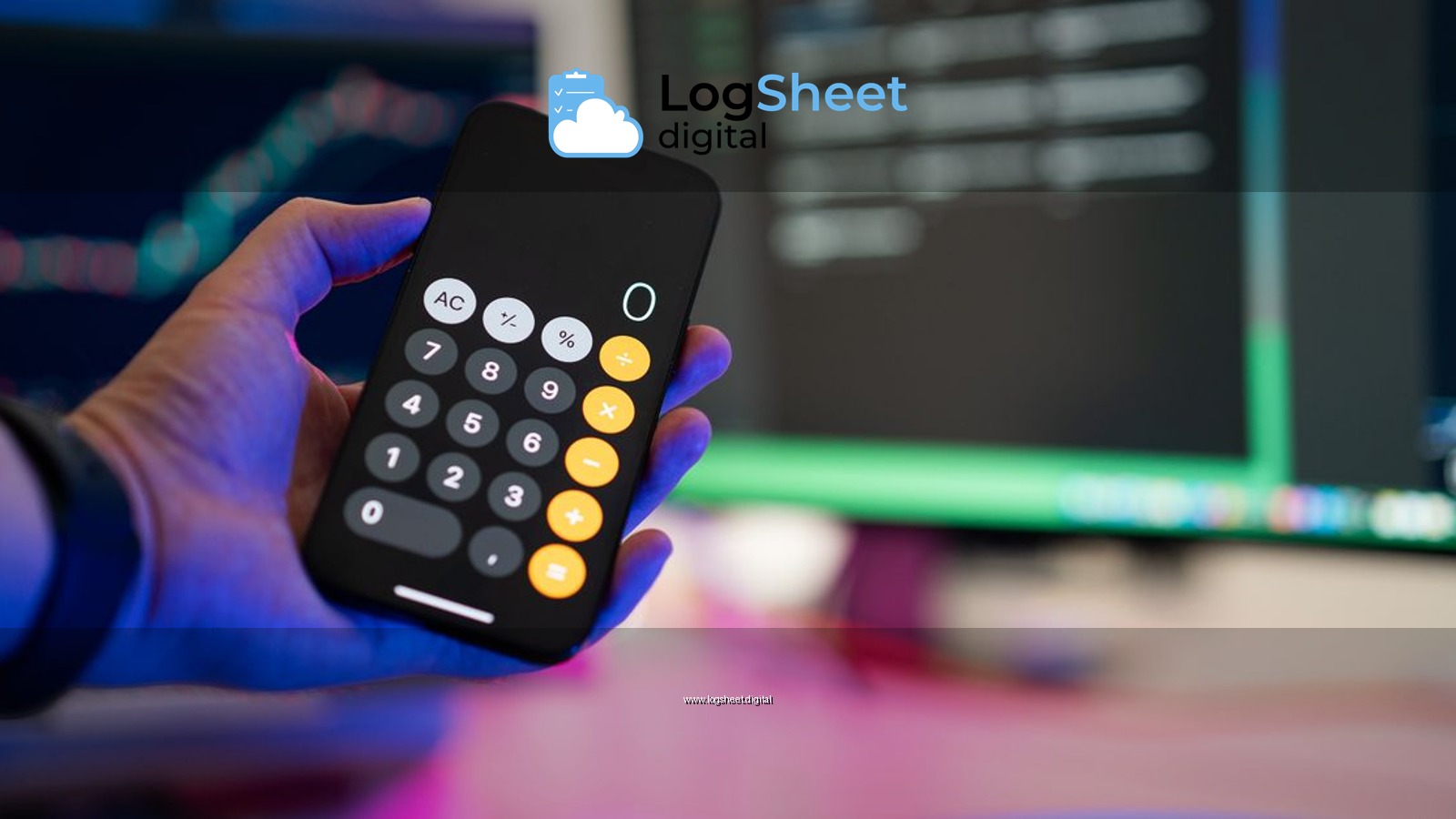 A person uses a smartphone calculator app in a modern office with computer screens displaying charts.