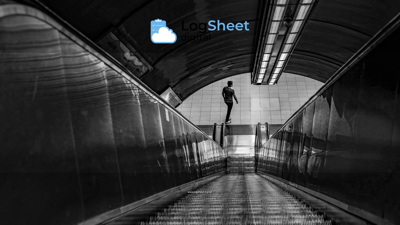 Dramatic black and white photo capturing a lone person on an escalator inside a subway station.